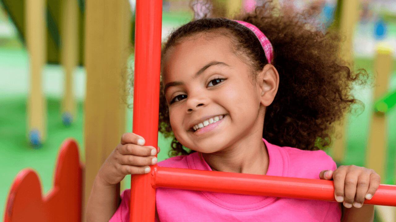 Child Smiling on Playground and Looking Happy