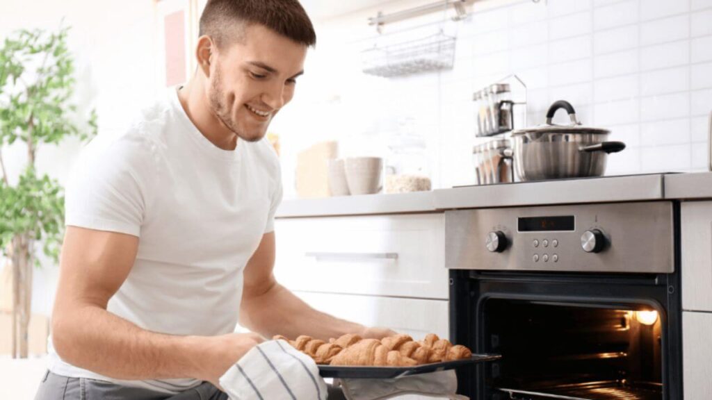 Man Baking Taking Baked Goods From Oven