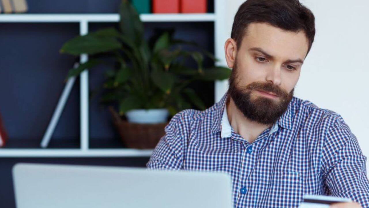 Man Looking Sadly at His Credit Card