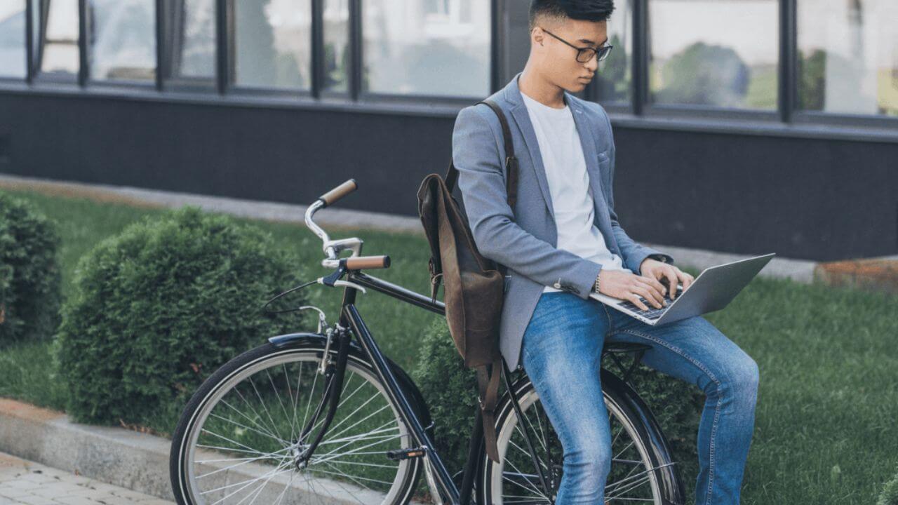 Man Sitting on His Bike While Using Laptop