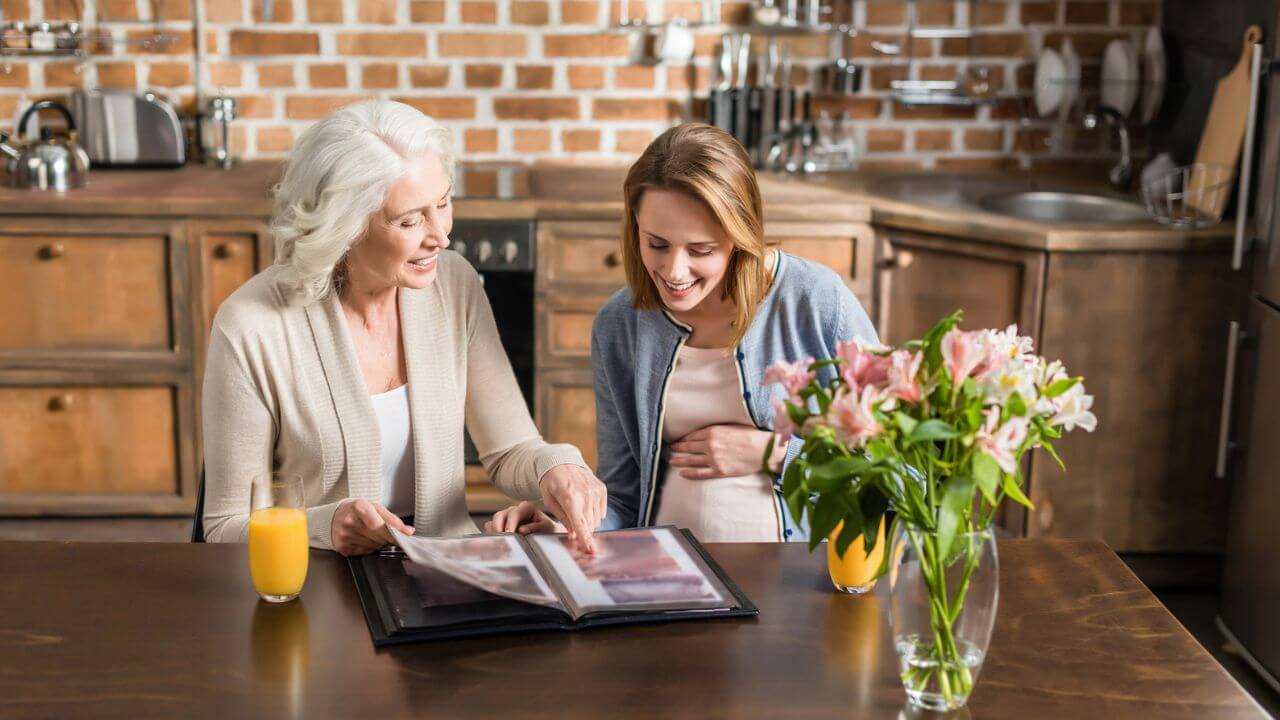 Pregnant Woman and Her Mother on the Kitchen Looking at the Photo Album