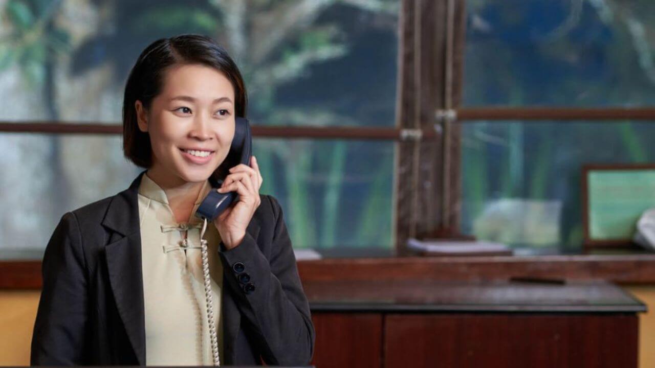 Receptionist At A Desk Calling Phone