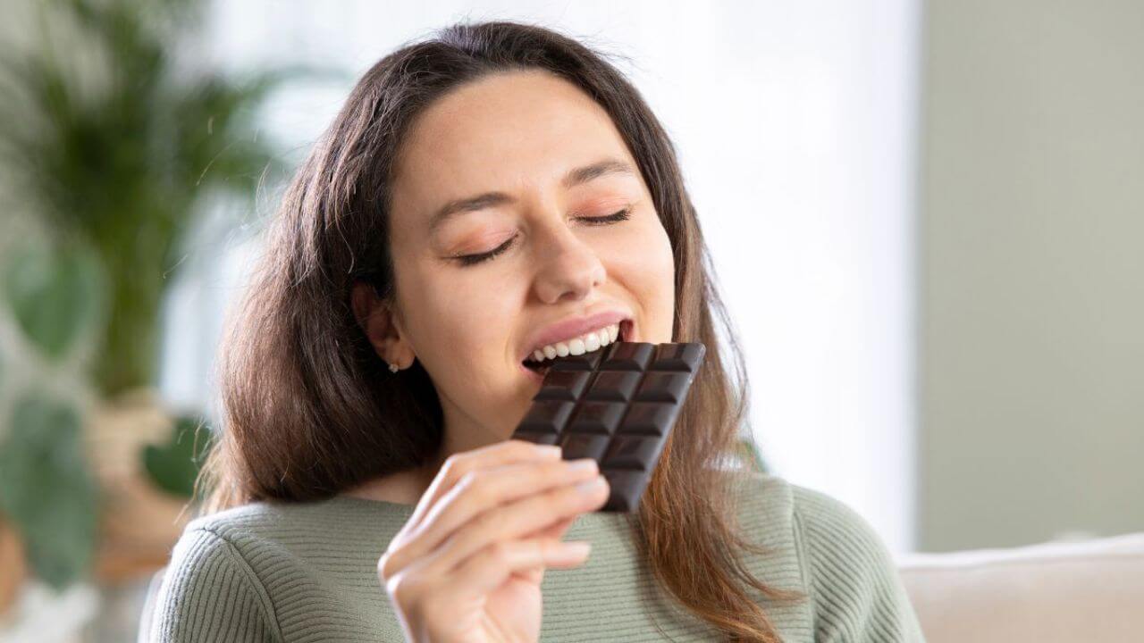 Woman Deliciously Eating a Bar of Dark Chocolate