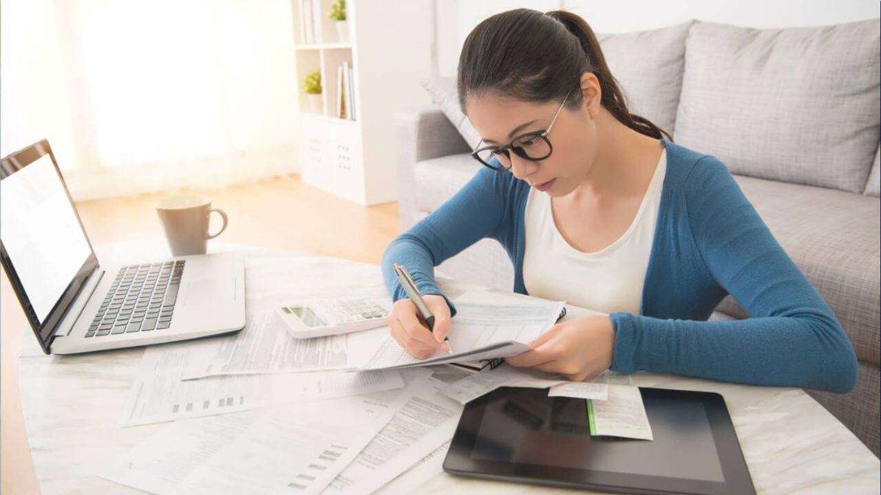 Woman Using Laptop and Tablet To Calculate Bills