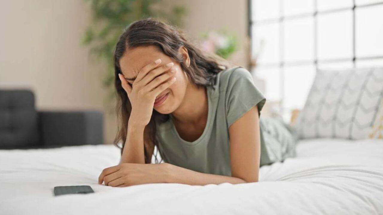 Woman in Bed Covering Her Eyes With One Hand Crying