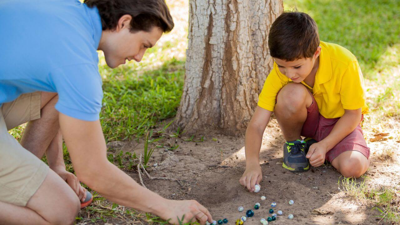 Young Boy Playing Marbles with His Dad in the Yard